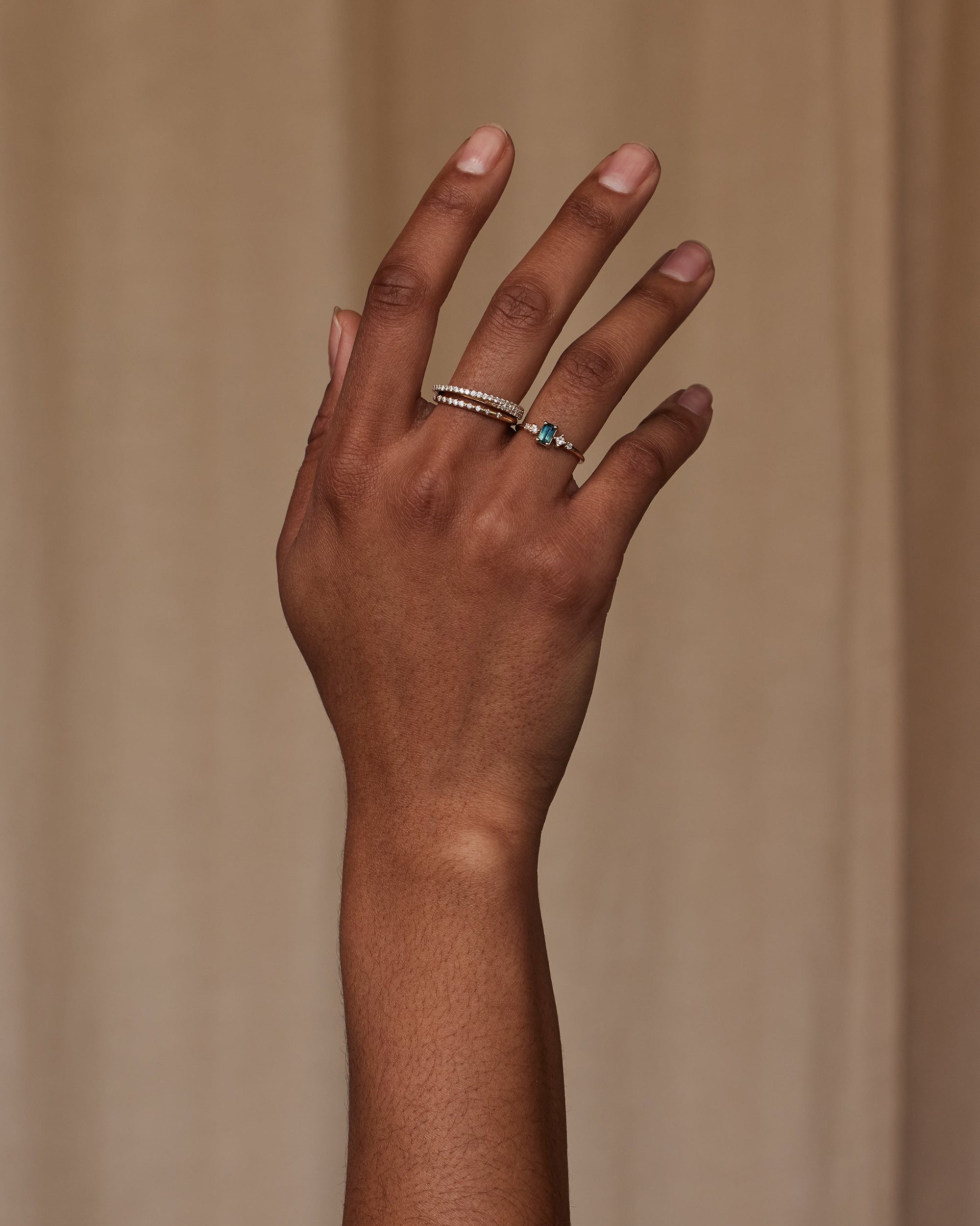 [lifestyle]Hand wearing two rings on a beige background