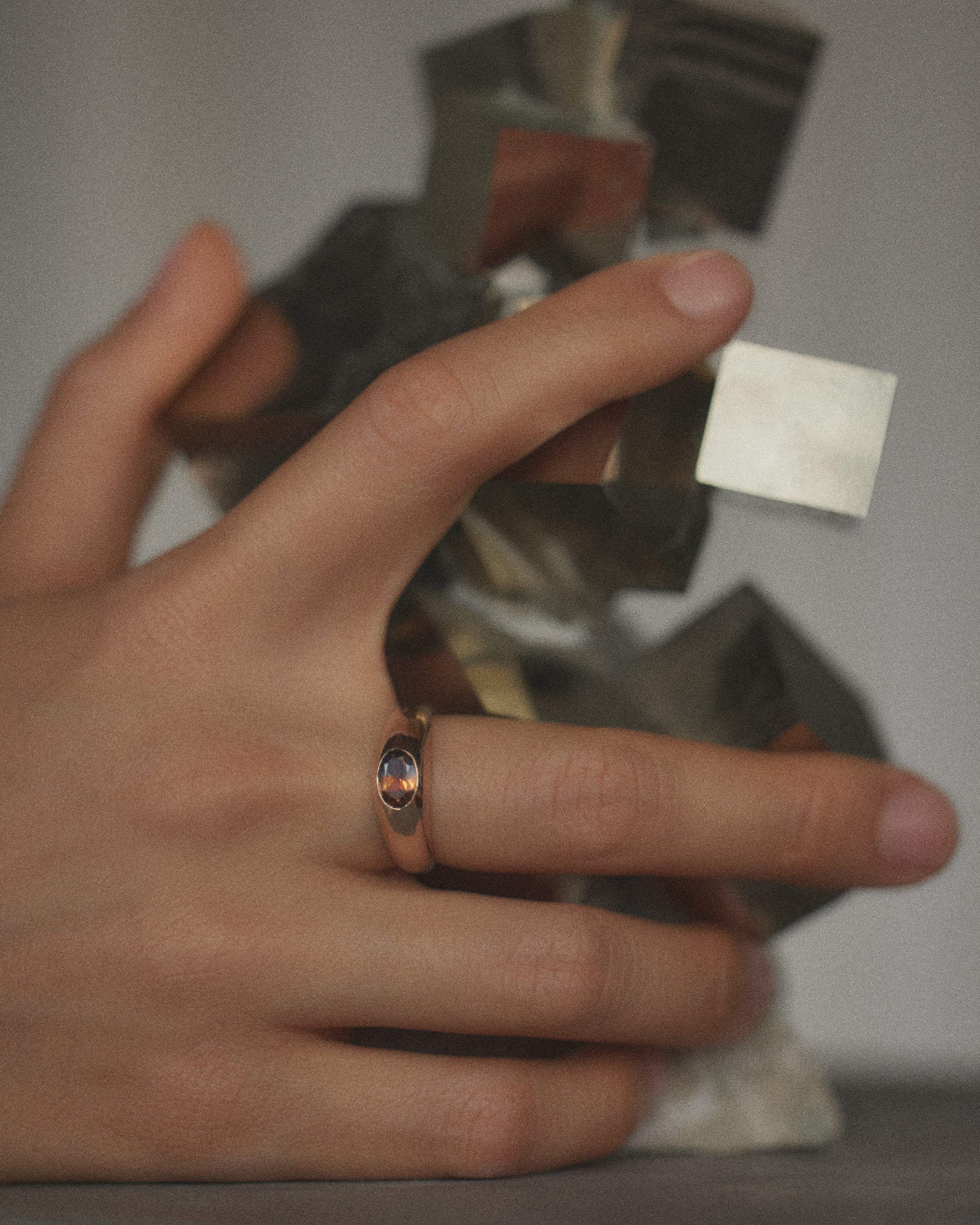 [lifestyle]Hand wearing a gold ring with a blurred background