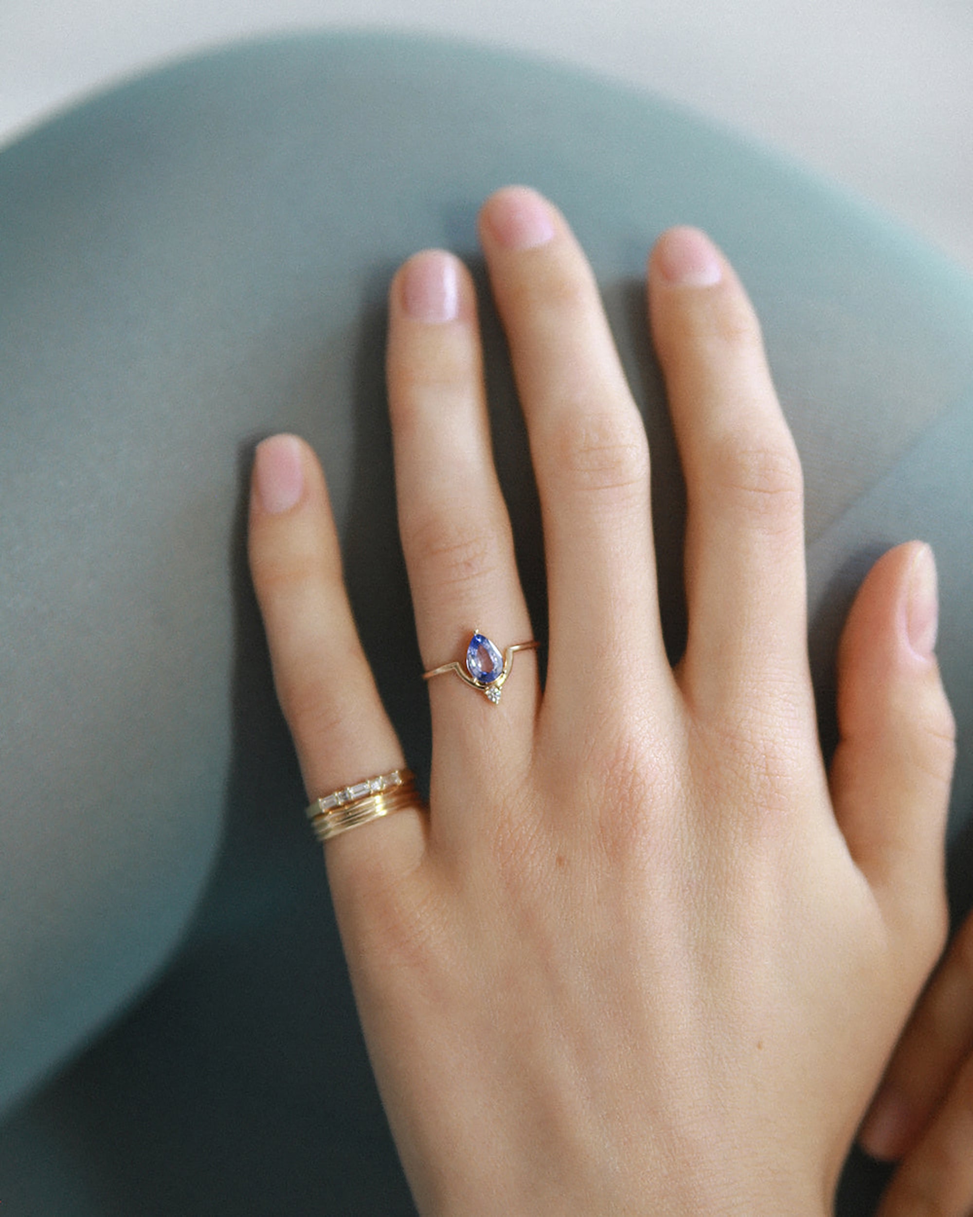 [lifestyle]Hand wearing two rings on a neutral background
