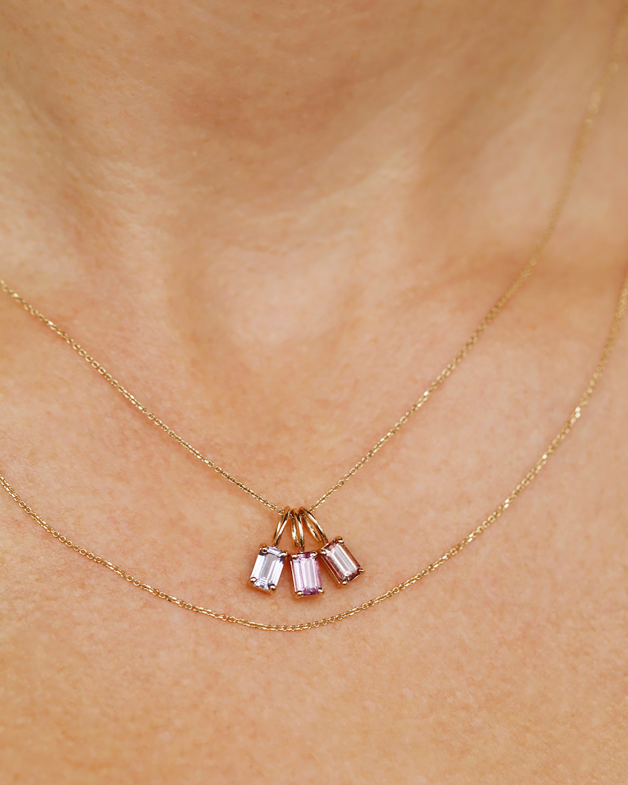 [lifestyle]Gold necklace with three gemstones on a person's neck